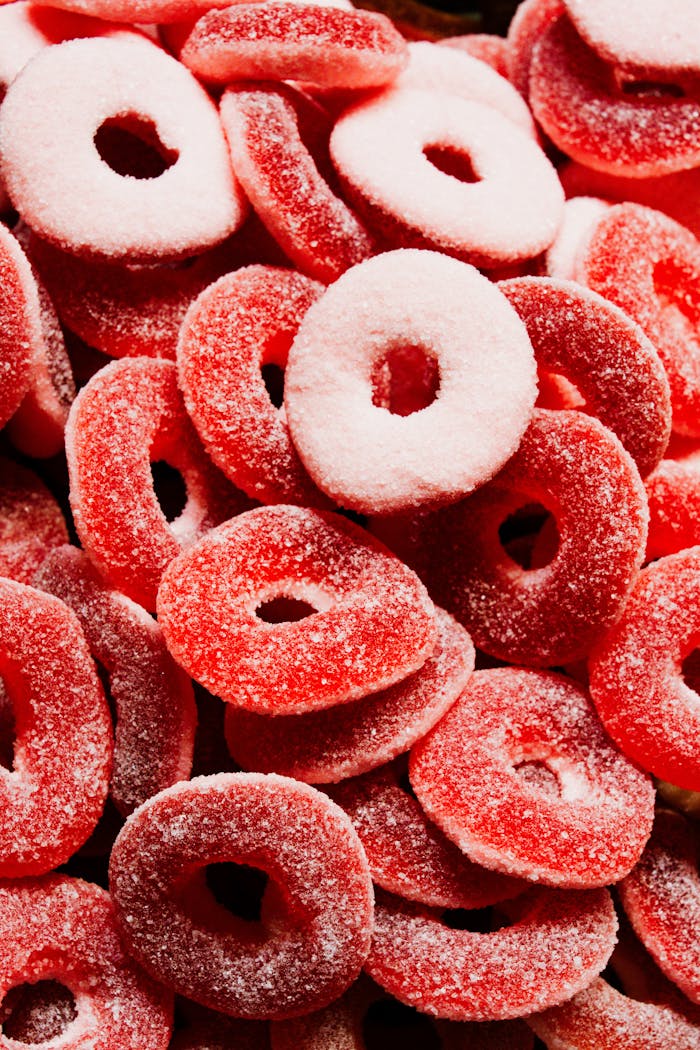 Pile of sugary red peach ring candies creating a colorful and sweet texture.